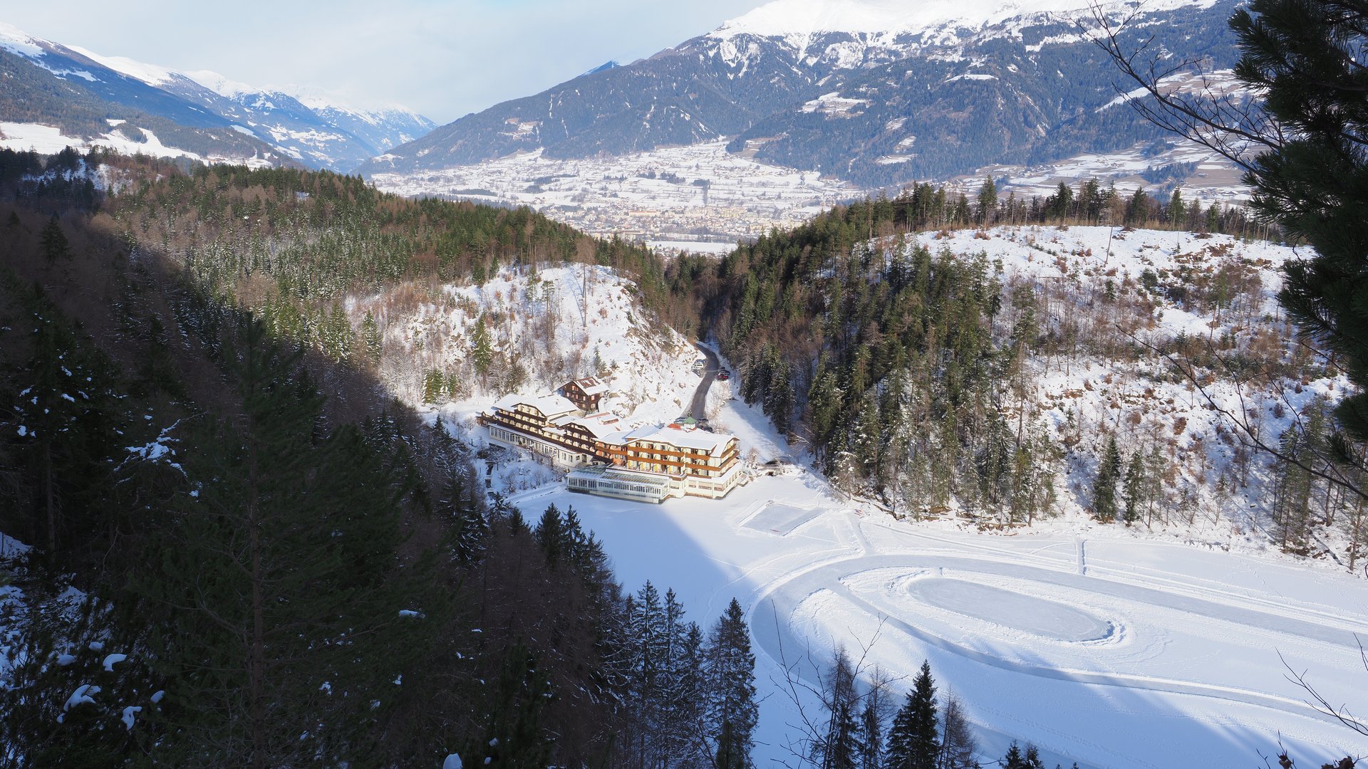 Winterliches Berghotel Verschneites Hotel in den Bergen, umgeben von Bäumen und majestätischem Panorama.